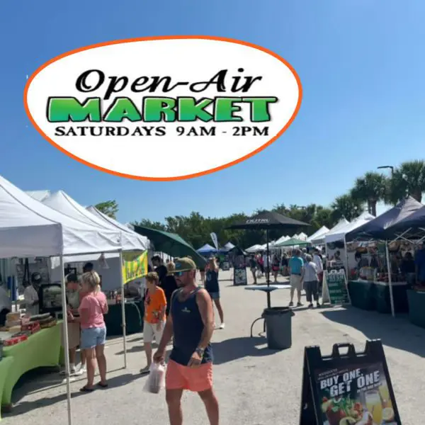 Outdoor market with vendors and shoppers under tents on a sunny day.
